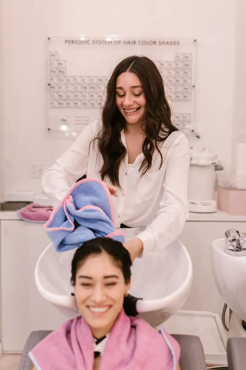 Stylist smiling while washing a smiling customer's hair